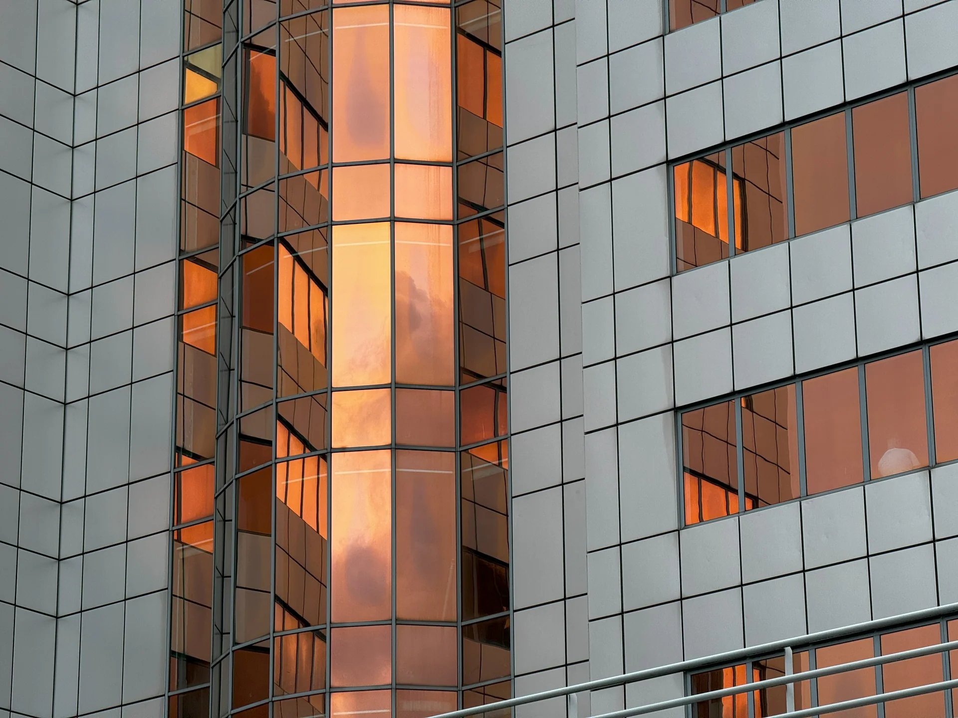 Graue Gebäudefassade mit orangefarbenen Glasreflexionen.