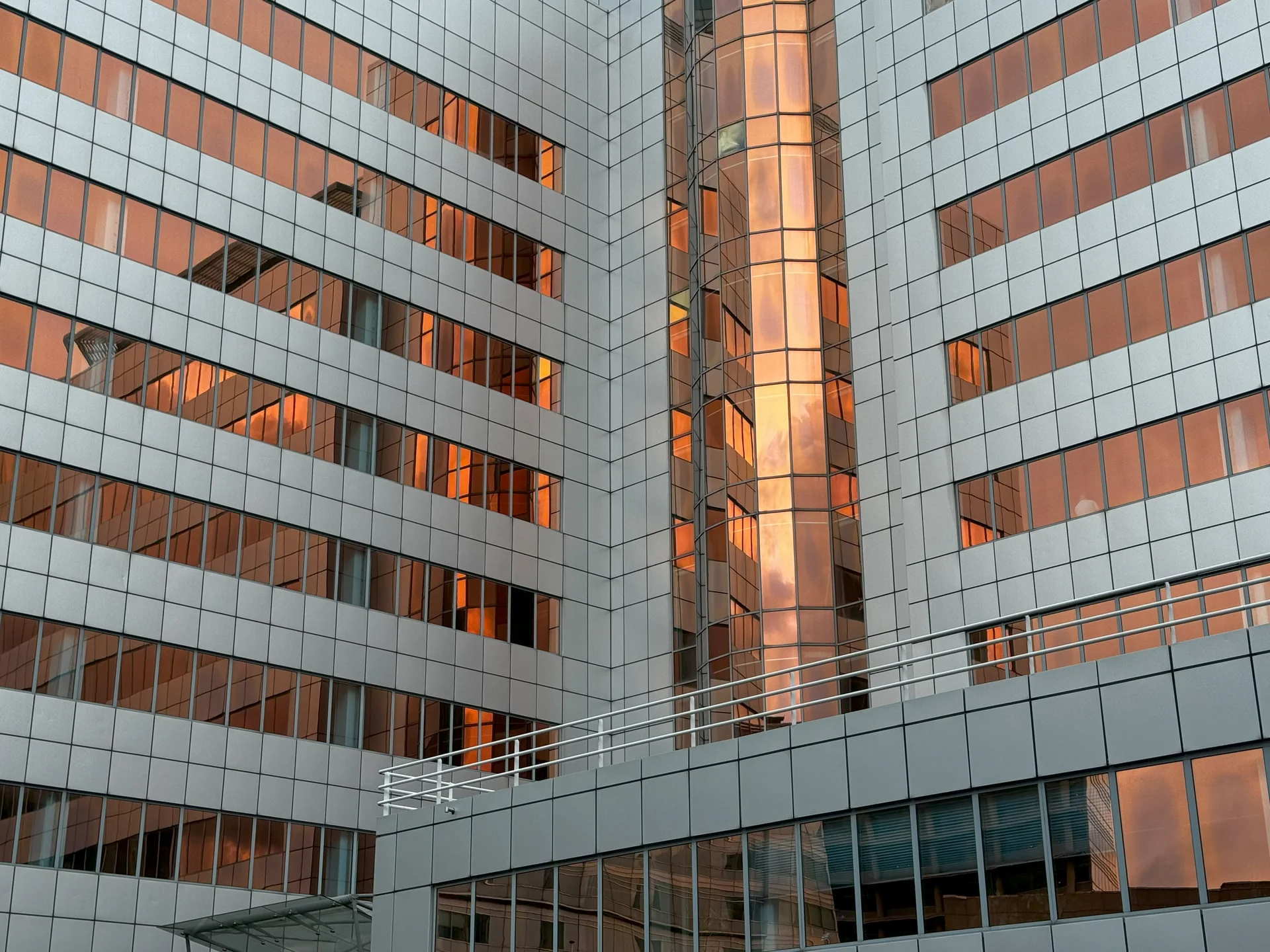 Moderne Gebäudefassade mit orange schimmernden Fensterflächen.